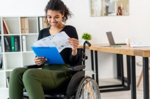 a young woman sitting in a wheelchair with papers and smiling