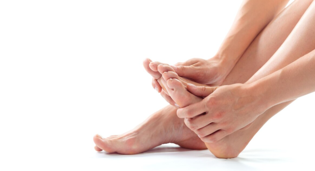 A person's hands gently holding their feet, suggesting discomfort or self-examination