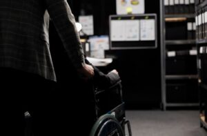 Silhouette of a person in a wheelchair from behind looking towards a screen with charts