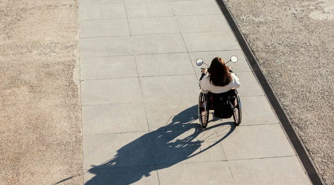 a person in a wheelchair moving along a paved path