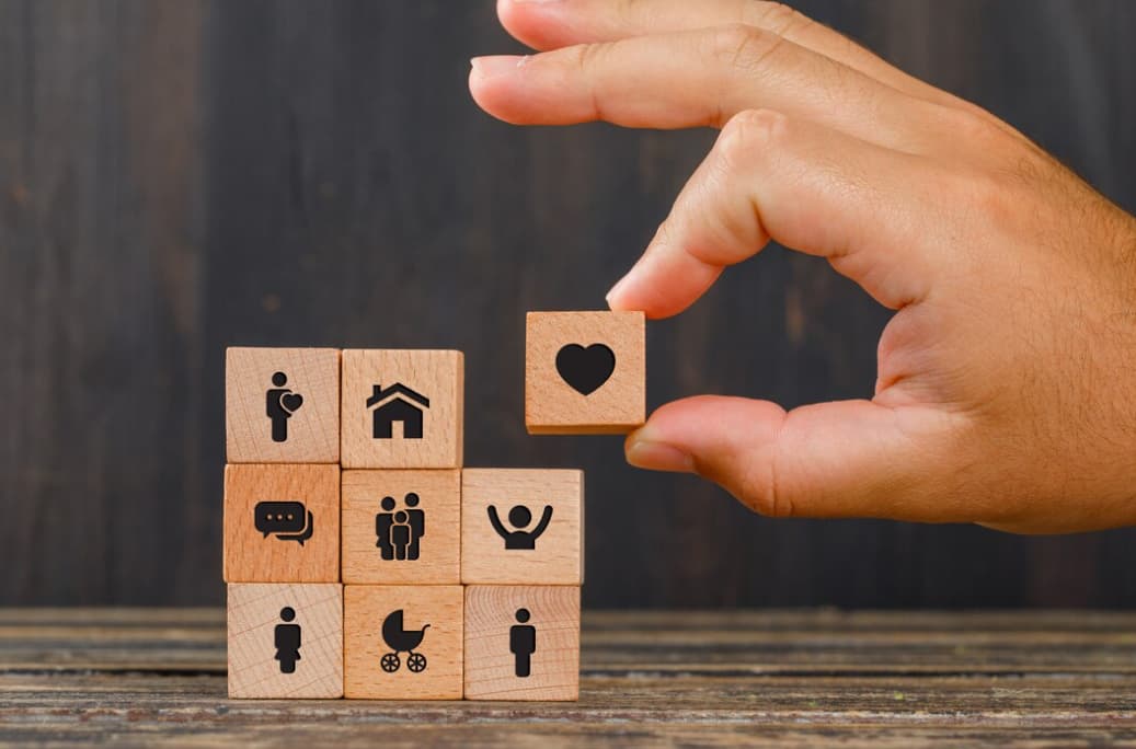 the wooden cubes and hand putting a wooden cube with a heart on the top of the bunch